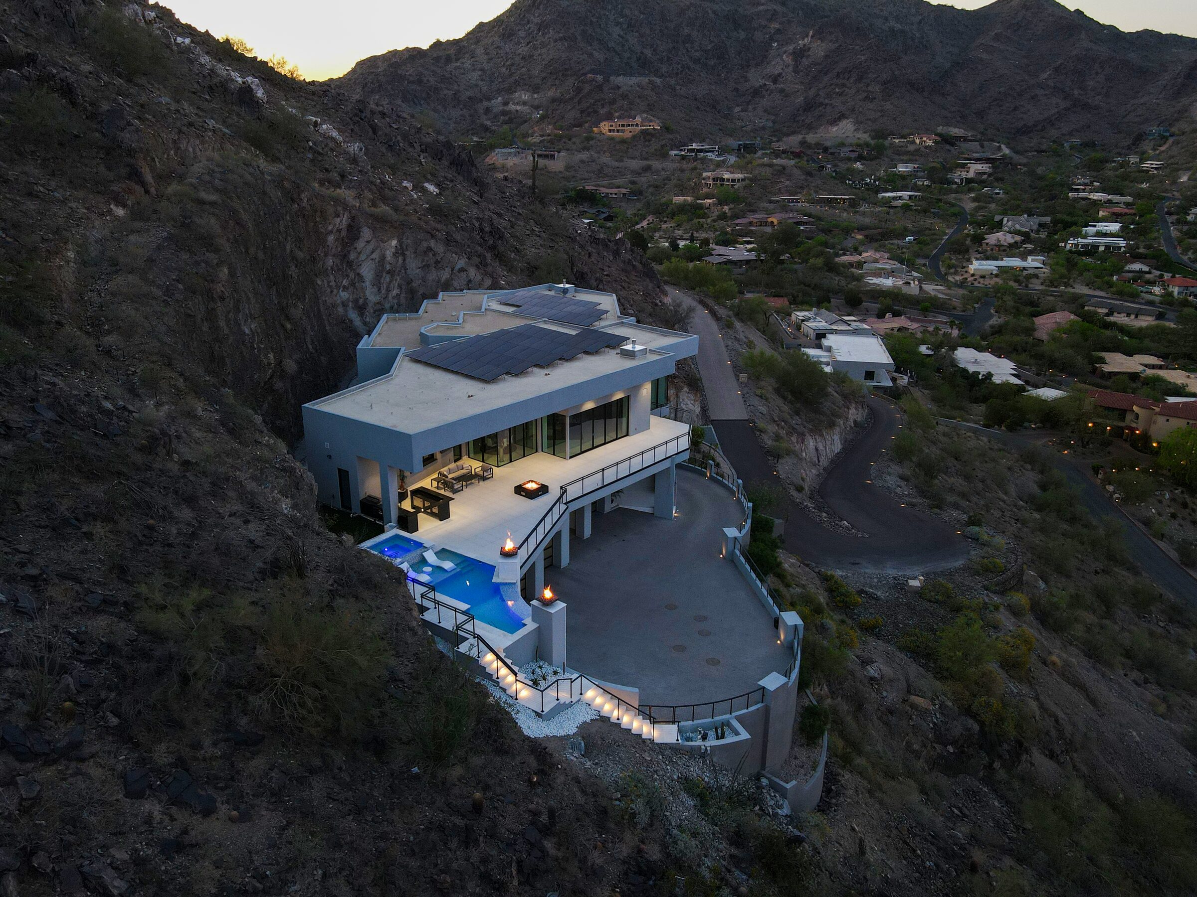 Aerial view of luxury hillside estate with multi-level infinity pool and outdoor living spaces built into Paradise Valley mountainside